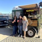 Three staff members smiling, in front of the La Vida Oats cart.
