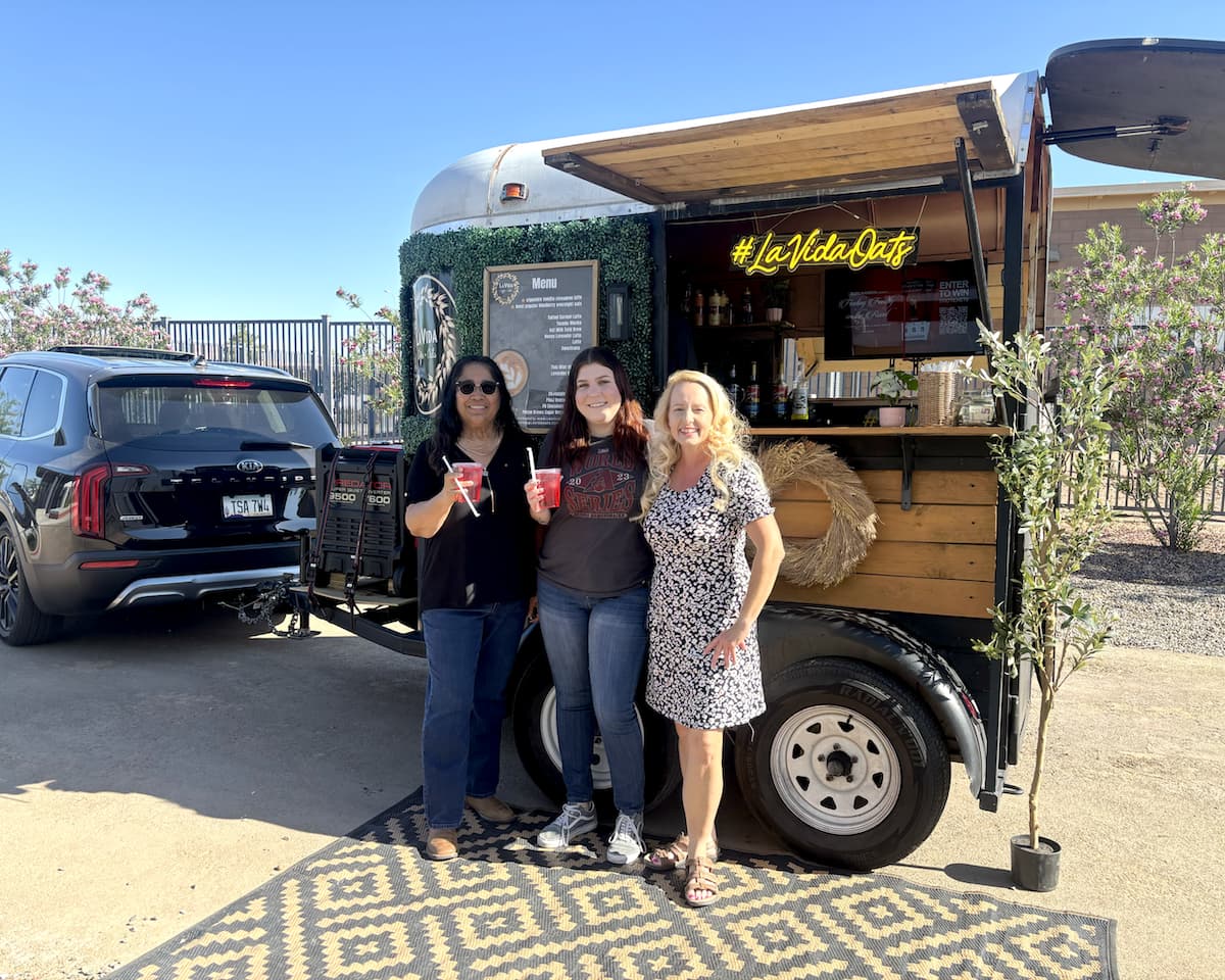 Three staff members smiling, in front of the La Vida Oats cart.